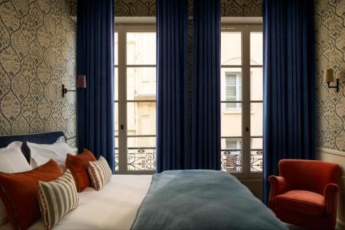 a bedroom with a bed and a window and a chair at Hotel des Orfèvres in Paris