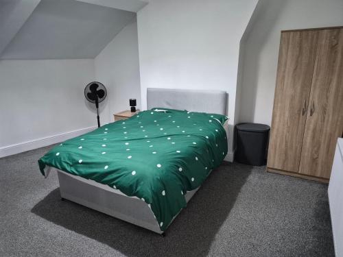 a bedroom with a green comforter on a bed at Double rooms in Crosby
