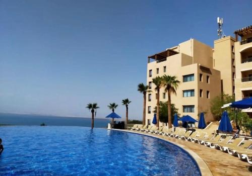 a large swimming pool next to a building with palm trees at Samarah EP 04 full Sea View and poll access prime location with big terrace, in Sowayma
