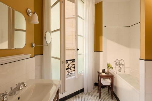a bathroom with a tub and a sink at Hotel des Orfèvres in Paris