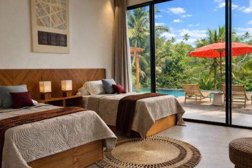 two beds in a room with a view of a pool at Oran Villa Bali in Tampaksiring