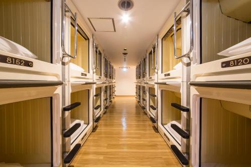 a long hallway with many empty shelves in a room at Shinjuku Kuyakusho-mae Capsule Hotel in Tokyo