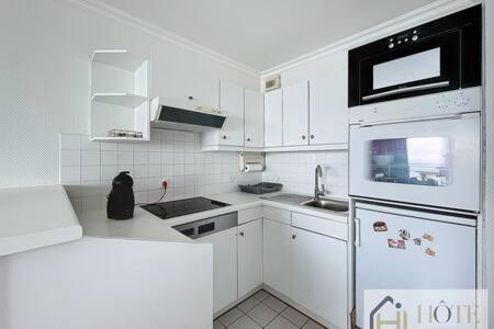 a small kitchen with white cabinets and a refrigerator at Le Panoramique Marin- 2Ch in Bray-Dunes