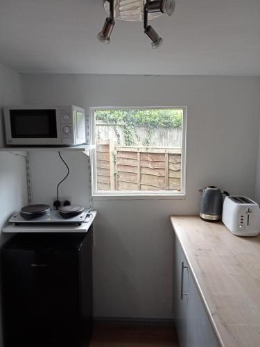 a kitchen with a stove and a window in it at Delightful cosy cabin in Margate
