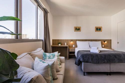 a hotel room with a bed and a couch at Duque by My Way - 100 meters from Santa Casa and UFRGS in Porto Alegre