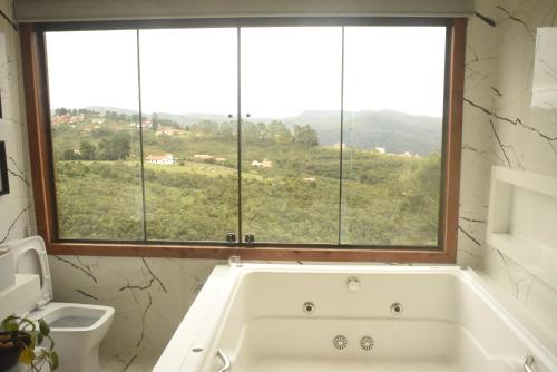 a bath tub in a bathroom with a window at Suítes e Loft do Tião in Lavras Novas