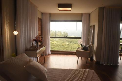 a bedroom with a bed and a desk and a window at Suítes e Loft do Tião in Lavras Novas