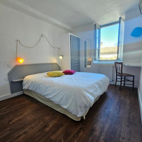 a bedroom with a bed and a desk and a window at Hôtel Candide in Saint-Bertrand-de-Comminges