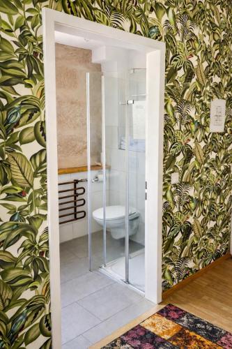 a bathroom with a toilet in a room with floral wallpaper at Hotel zum Rednitzgrund in Stein