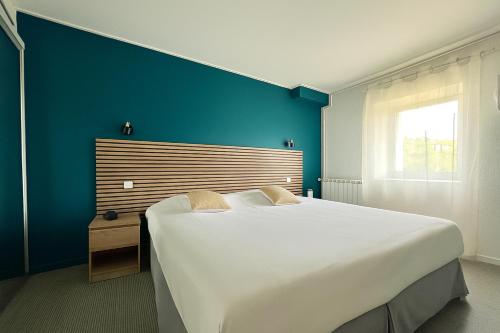 a large white bed in a room with a blue wall at Logis Hotel restaurant des Thermes in Lamalou-les-Bains