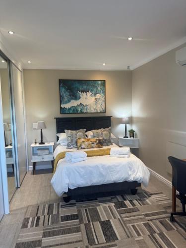 a bedroom with a large bed and a painting on the wall at Picasso's Cottage in Gqeberha