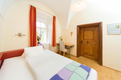 a bedroom with a bed and a desk and a window at AndersOrt Haus der Frauen in Buchberg bei Herberstein