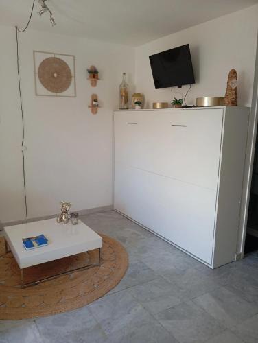 a living room with a white refrigerator and a table at Monplaisir in Fréjus