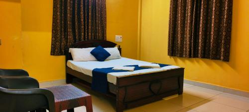 a small bedroom with a bed and a chair at Aadhya guest house in Tiruvannāmalai