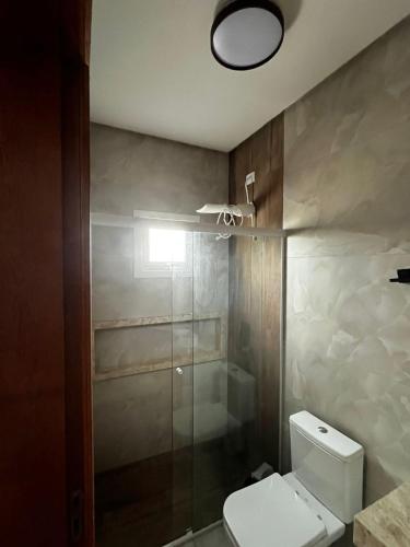 a bathroom with a toilet and a glass shower at Refúgio Rossa in Xangri-lá