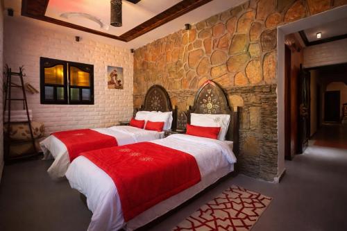 two beds in a room with a stone wall at Dar izem in Tafraout