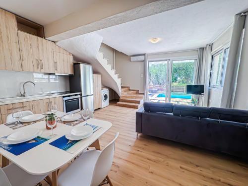 a kitchen and living room with a white table and chairs at Seaside Pool Villas by BookVillaEU in Nea Kallikrateia
