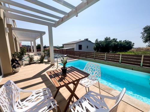a patio with a table and chairs and a pool at Seaside Pool Villas by BookVillaEU in Nea Kallikrateia