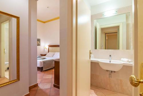 a bathroom with a sink and a mirror and a bed at Hotel Cimabue in Florence