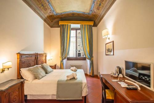 a bedroom with a bed and a table and a desk at Hotel Cimabue in Florence