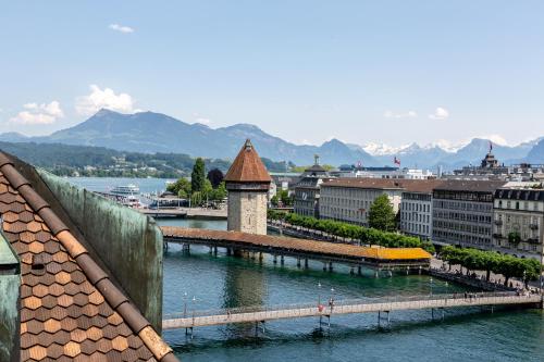 a bridge over a river in a city with mountains at Hotel des Balances in Lucerne