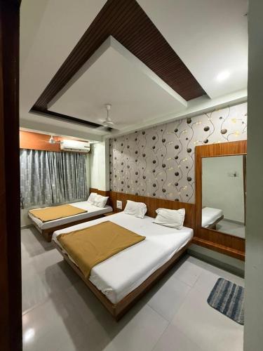a bedroom with two beds and a mirror at Hotel Sumeet Palace in Shirdi