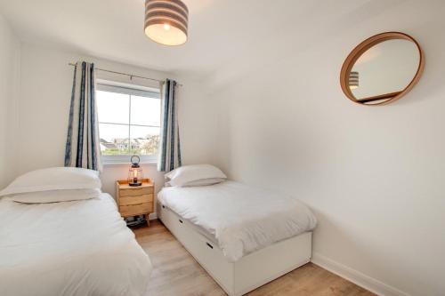 two beds in a room with a mirror and a window at 2 Bed in Woolacombe oc-beache in Woolacombe