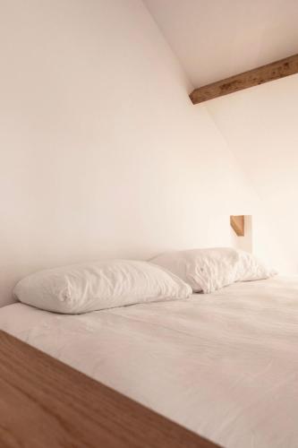an unmade bed with white sheets in a white room at Boerderij de Voorste Eng in Otterlo