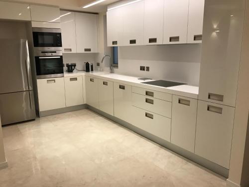 a kitchen with white cabinets and a refrigerator at Olympic Residence Deluxe Apartments in Limassol