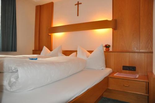 a bedroom with a white bed with a cross on the wall at Ferienwohnungen Durst Roswitha in Schattwald