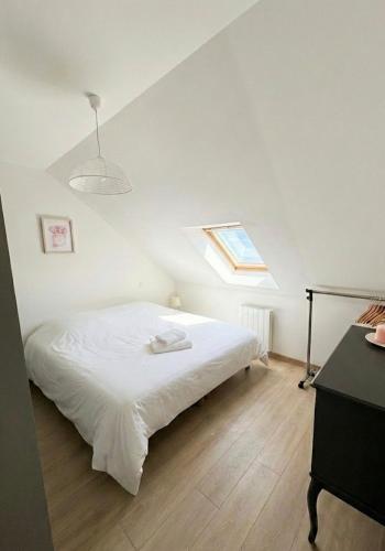 a bedroom with a white bed with a window at La perle du Centre à Cancale in Cancale