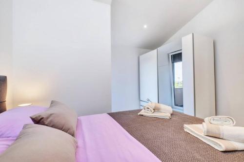 a white bedroom with a bed and a mirror at Beautiful new apartment Blaz in Mali Lošinj
