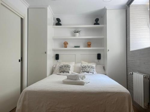 a bedroom with a bed with white walls and shelves at ALAIA Mundaka in Mundaka