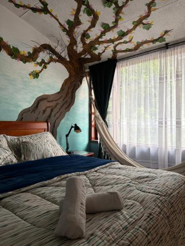 a bedroom with a bed with a tree on the wall at Casa Mood Usaquen in Bogotá
