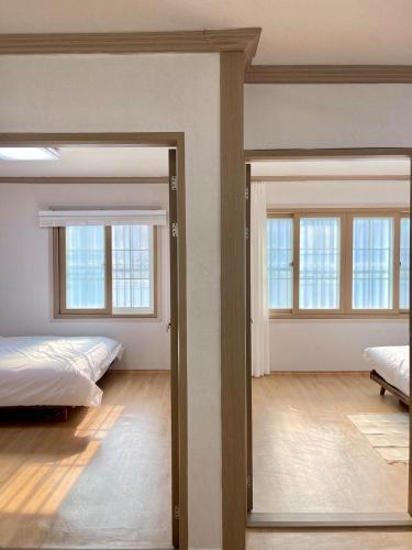 a bedroom with two beds and two windows at Gaegum Moonlight Stay in Busan