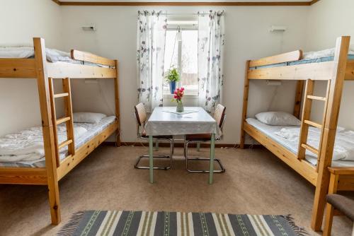 a room with a table and two bunk beds at Öje Vandrarhem & Turistgård in Östra Öje