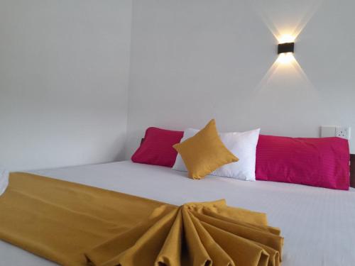 a bed with several different colored pillows on it at Sunshine Holiday Inn Ella in Ella