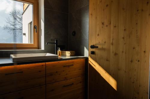 a bathroom with a sink and a wooden door at Chalet Astra, Whirlpool & Sauna in San Pancrazio dʼUltimo