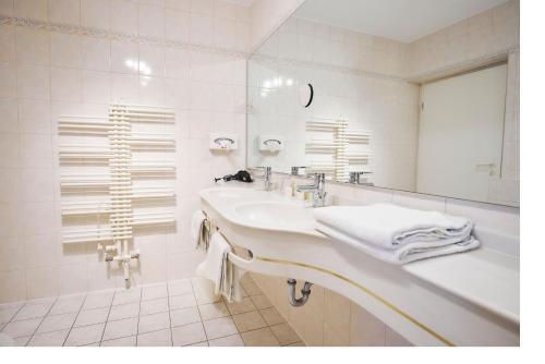 a white bathroom with a sink and a mirror at Flair Hotel Vier Jahreszeiten in Bad Urach