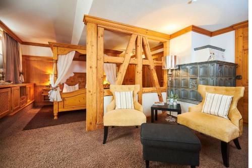 a bedroom with a canopy bed and two chairs at Flair Hotel Vier Jahreszeiten in Bad Urach