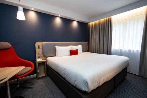 a hotel room with a bed and a red chair at Holiday Inn Express Canterbury by IHG in Canterbury