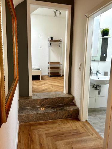 a hallway with stairs leading to a bathroom with a sink at modernes Apartment mit Wlan in Lorsch