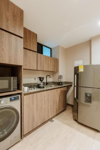 a kitchen with wooden cabinets and a stainless steel refrigerator at Cozy Loft in Class 48 in Sabaneta
