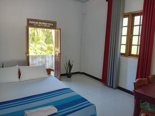 a bedroom with a large bed and a window at Duncan Murray Villa in Hambantota