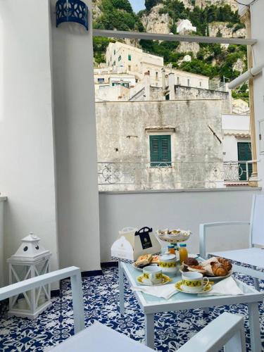 a table with food on a balcony with a view of a building at Dolce Pausa in Atrani