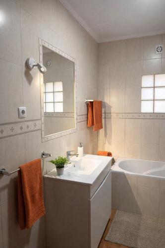 a bathroom with a sink and a tub and a mirror at Cantinho do Sol in Mosteiros