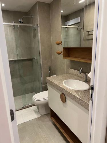 a bathroom with a toilet and a glass shower at Beach Class Verano - Resort em Muro Alto por Yolo in Ipojuca