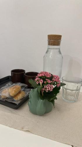a table with a vase with flowers and a bottle at London Cozy Room, Fast WiFi in London