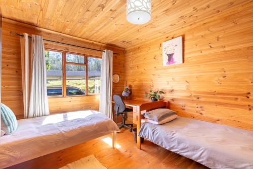 a bedroom with two beds and a desk in a log cabin at Summer Villa in Mossel Bay