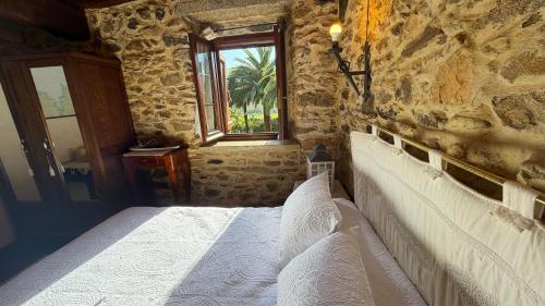 a bedroom with a bed in a stone wall at Rego de Cora By Oktheway in Valcarría
